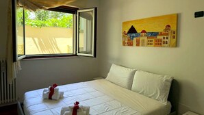 Ein Hotelzimmer mit Bett, einem Bild an der Wand und einem Fenster mit Blick auf Grünfläche.