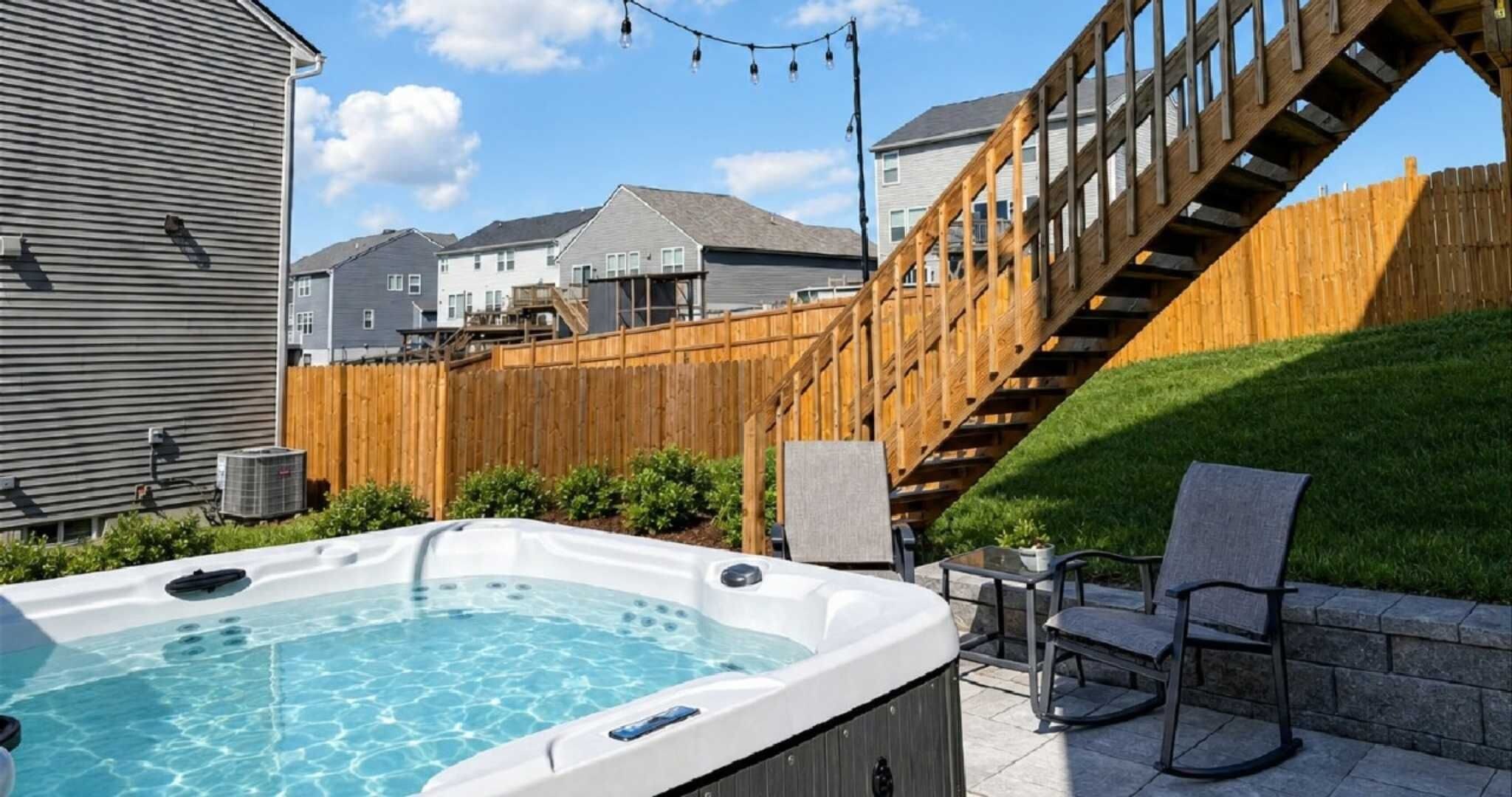 Ein Garten mit einem Whirlpool, einer Holzdiele und einer Treppe, die zu einem Haus führt.