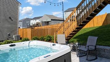 Ein Garten mit einem Whirlpool, einer Holzdiele und einer Treppe, die zu einem Haus führt.