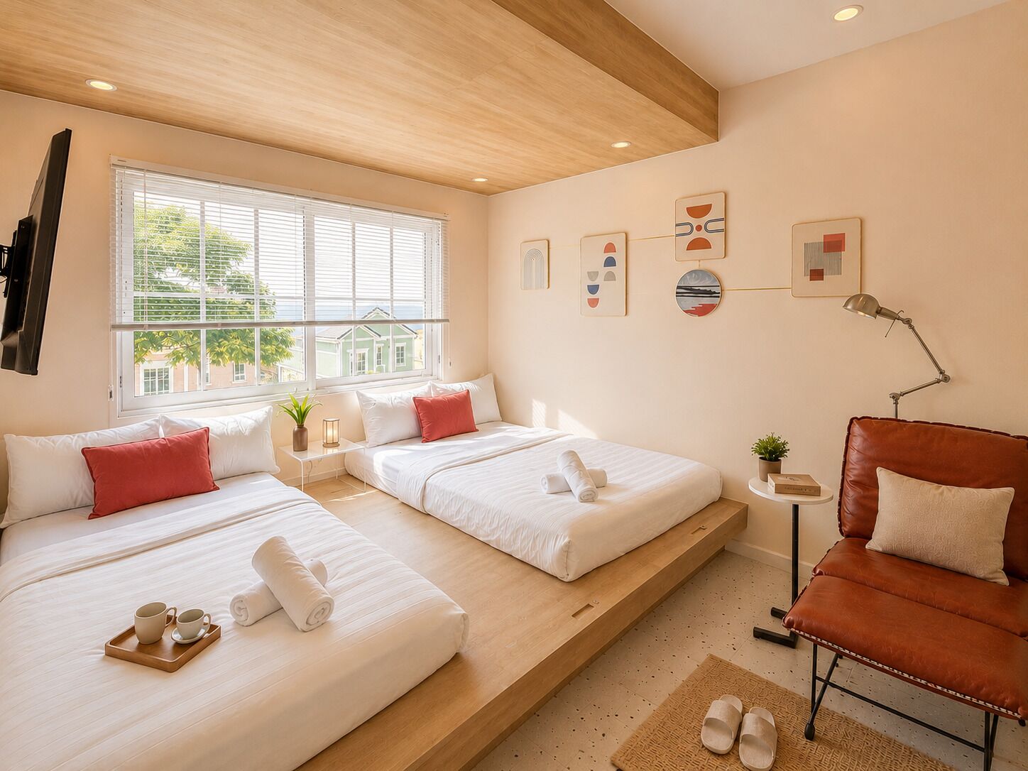 A hotel room with two beds, a small table, a chair, and artwork on the walls.