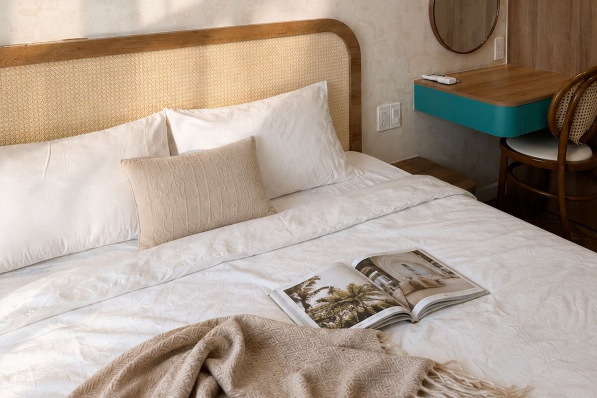 A bedroom with a bed, a bedside table, a chair, and a wall-mounted mirror.