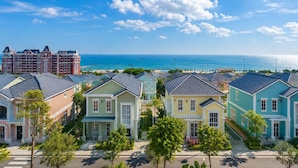 A coastal residential area with colorful houses, a large building with a tower, and a view of the ocean. - Novaworld Phan Thiet - Mira Villas (Tien Thanh)