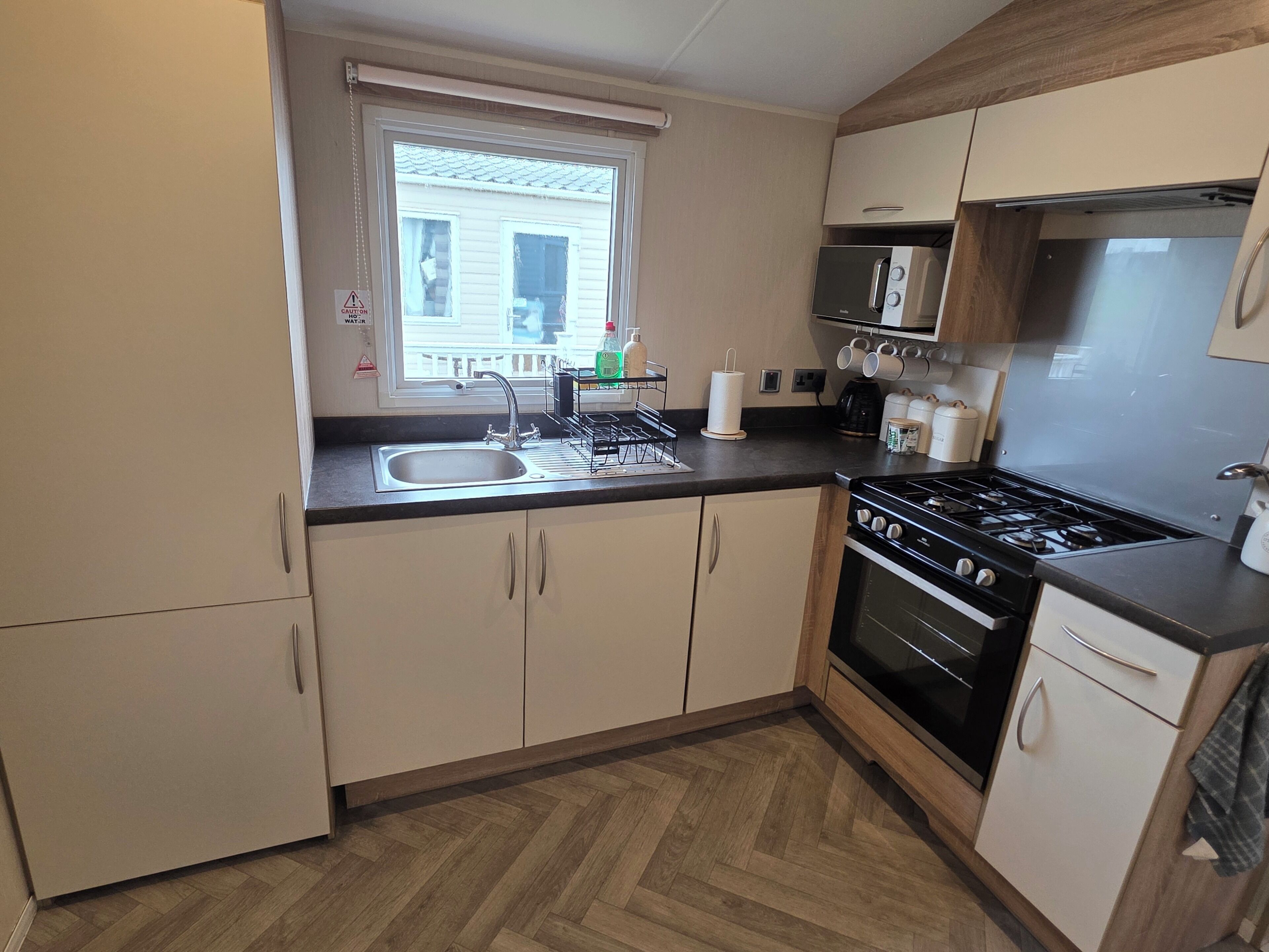 A compact kitchen with a sink, stove, microwave, and cabinets.