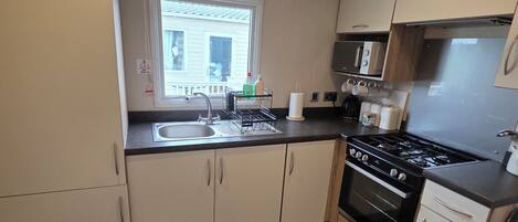 A compact kitchen with a sink, stove, microwave, and cabinets.