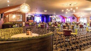 Een ruime hotellobby met diverse zithoeken, een opvallend menubord en een grote kaart aan de muur.