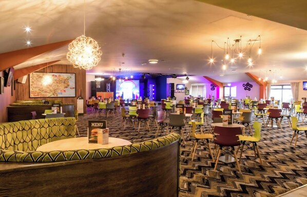 A spacious hotel lobby with a variety of seating options, a prominent menu board, and a large map on the wall.