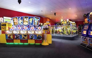 Une salle d’arcade lumineuse, avec de nombreux jeux et des écrans aux couleurs vives.