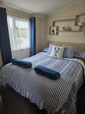 A neatly made bed with striped bedding, a headboard, and a window with curtains.