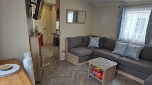 Een moderne woonkamer met een hoekbank, een kleine houten tafel en een vloer met een herringbone-patroon.