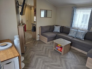 A modern living room with a sectional sofa, a small wooden table, and a herringbone-patterned floor.