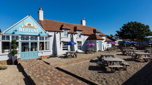 Een pub genaamd 'Neptune' met terras en een met bakstenen bestraat pad dat naar de ingang leidt.