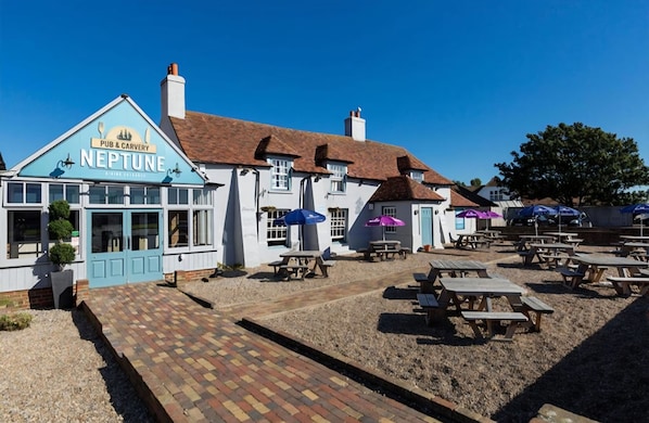 A pub named 'Neptune' with outdoor seating and a brick pathway leading to the entrance.