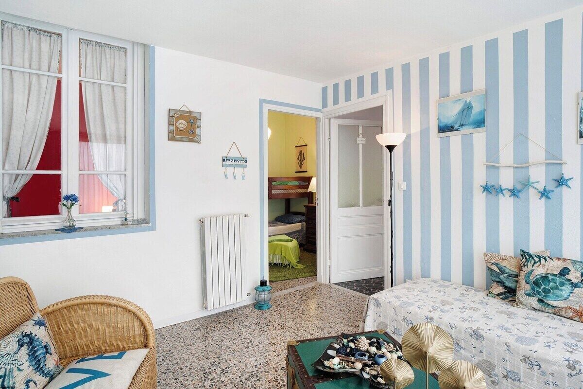A room with a bed, a wicker chair, a table with a tray of snacks, a radiator, a lamp, and a striped wall.