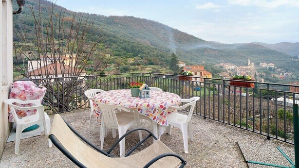 Un balcón con mesa y sillas, con vistas a un paisaje montañoso.