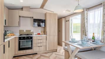 A modern kitchen with a dining area, a view through the window, and a table set for dining.
