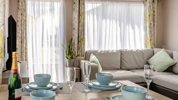 A dining area with a table set for four, a bottle of champagne, and a sofa in the background.