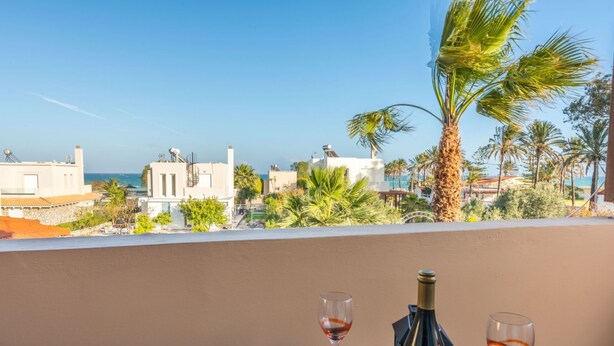 Een balkon met een tafel, twee wijn glazen en een fles wijn.