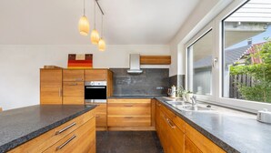 A modern kitchen with wooden cabinets, a built-in oven, and a large window.
