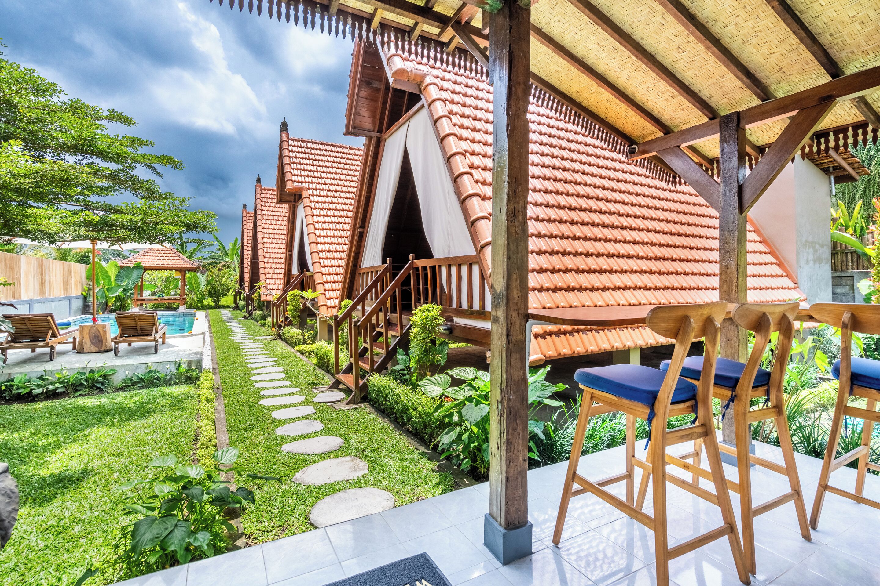 Una casa tradicional con techo de tejas, piscina y jardín con piedras para caminar.