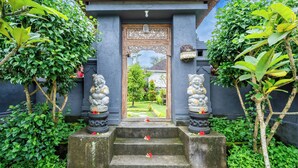 Tempelentree met een houten deur, treden die erheen leiden, en beelden aan weerszijden.