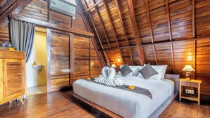 Een kamer met houten lambrisering, een bed, nachtkastje, dressoir en een raam.