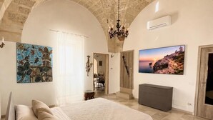 Ein Schlafzimmer mit einem großen Bett, einer Kandelaber, einem Gemälde und einem Fernseher.