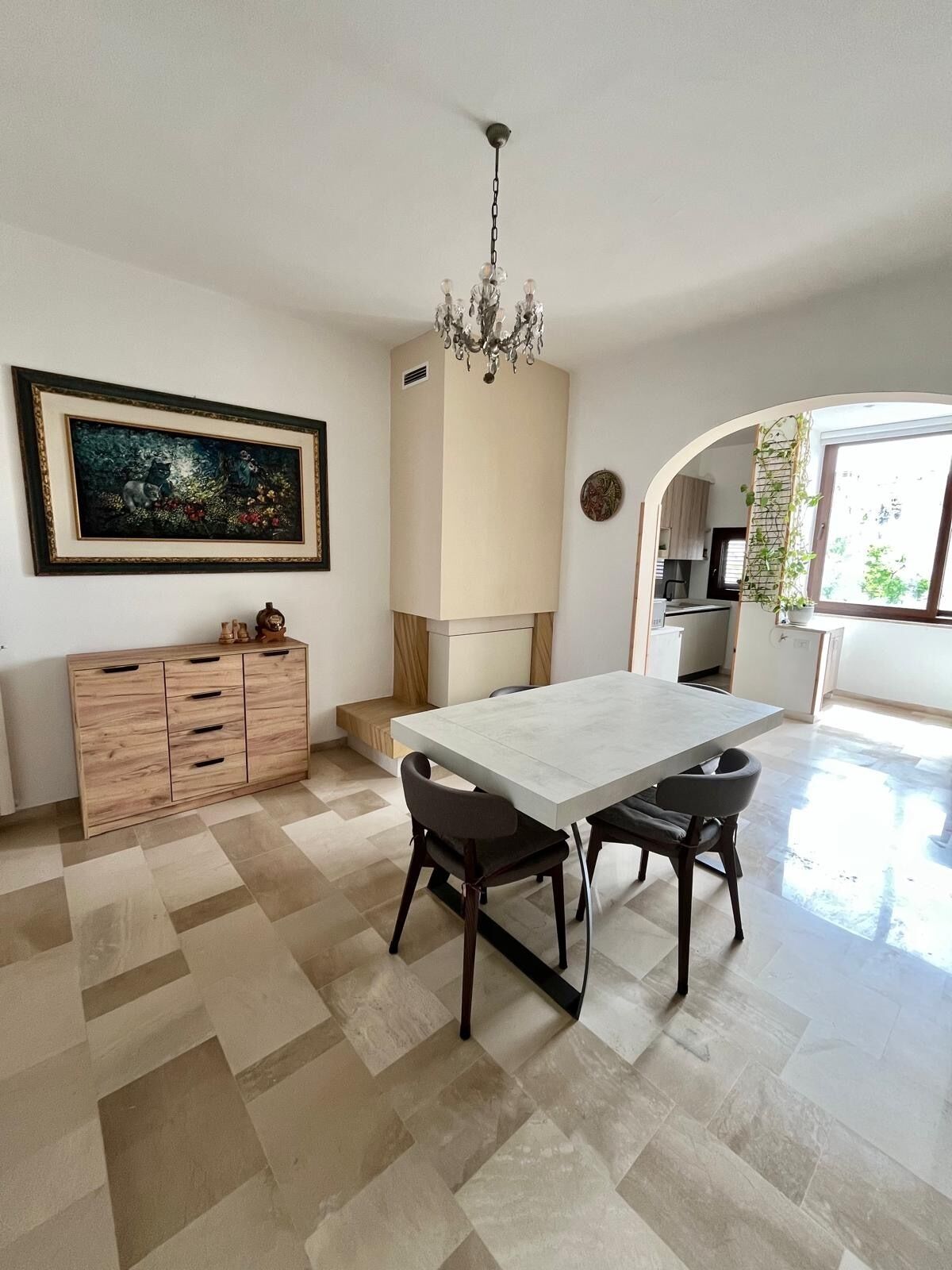 Uma sala de jantar espaçosa com uma grande mesa e cadeiras, um armário de madeira, um candelabro e um quadro na parede.