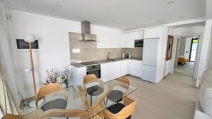 A modern kitchen with white cabinets, a stainless steel range hood, and a glass dining table with wooden chairs. - SUN SEA & LOVE: Beachfront villa 33 meters from the sand (Puerto Rico)