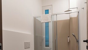 A modern bathroom with a glass-enclosed shower, two sinks, and a toilet. - Cozy twin room with private bathroom. (Livorno)