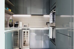A modern kitchen with stainless steel appliances, a built-in oven, and a wine rack. - Sleek 1BDR Flat with Balcony Private Work Space (Greater London)