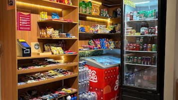 Uma loja Mercasa com prateleiras repletas de petiscos, um refrigerador de Coca-Cola e um balcão refrigerado.