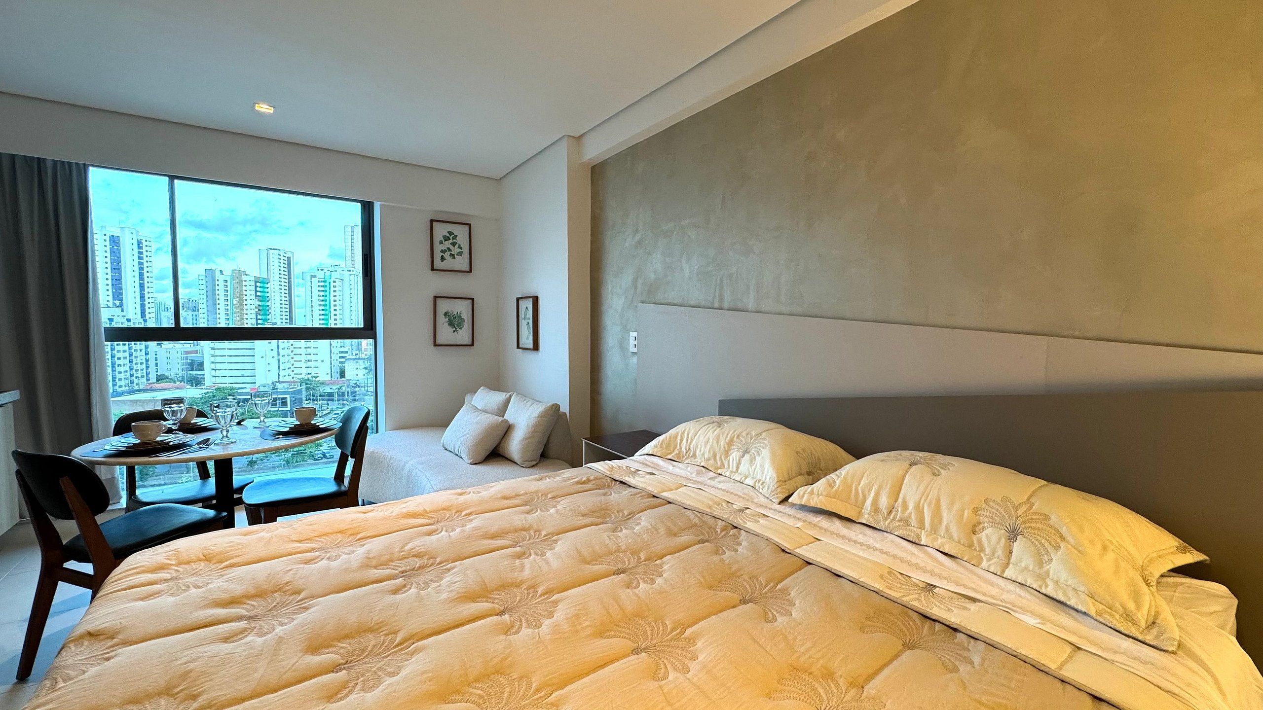 Quarto de hotel com uma cama grande, área de refeições e vista para a cidade.