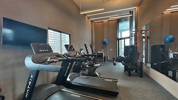 Uma academia com esteiras, bolas de exercícios e um espelho grande na parede.