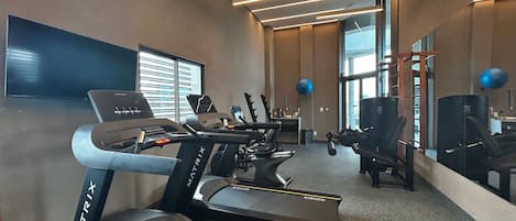 Uma academia com esteiras, bolas de exercícios e um espelho grande na parede.