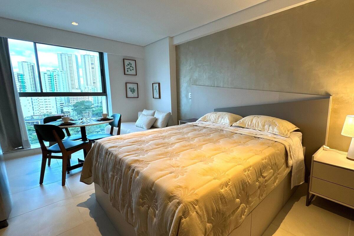 Quarto de hotel com cama grande, mesa de cabeceira e vista para a cidade.