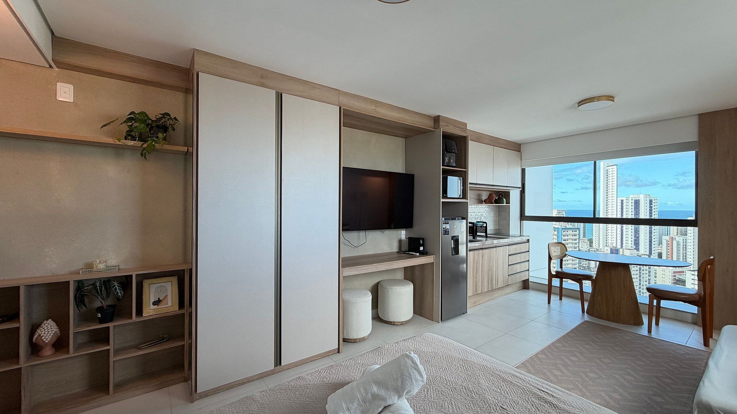 A modern apartment with a kitchen, dining area, and a large window with a city view.