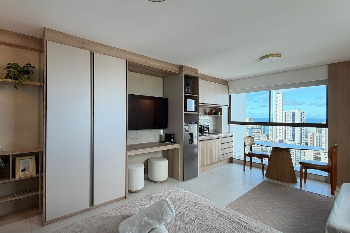 Um apartamento moderno com cozinha, área de jantar e uma grande janela com vista para a cidade.