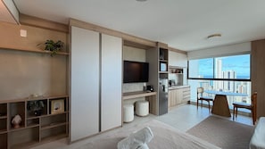 A modern apartment with a kitchen, dining area, and a large window with a city view.