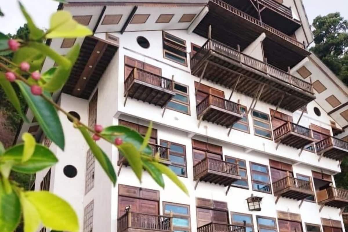 A multi-story building with balconies and a sandy ground.