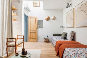 Une pièce comprenant un lit, une chaise, une petite table, une statue de Bouddha décorative et une porte.