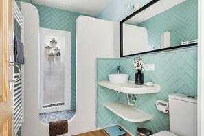 Et badeværelse med brusebad, toilet, vask og spejl.