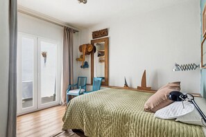 A bedroom with a bed, a chair, a mirror, and a window with curtains.