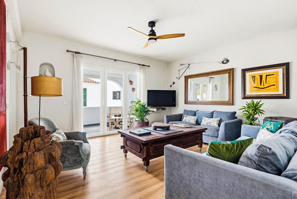 A living room with a sofa, armchair, coffee table, television, and decorative items.