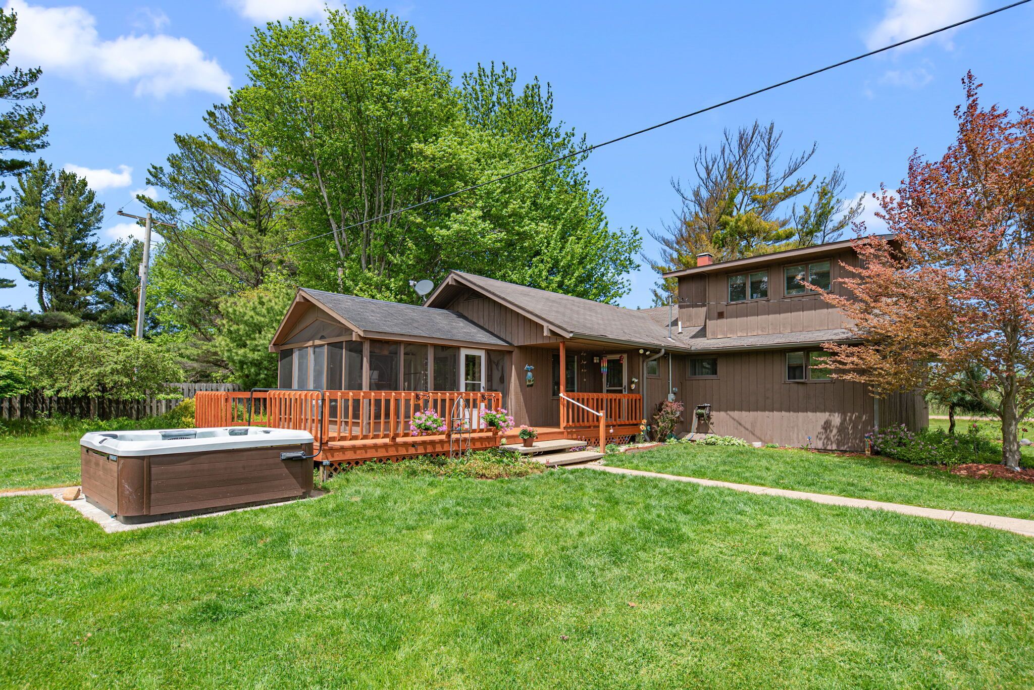 A two-story house with a deck, a hot tub, and a well-maintained lawn.