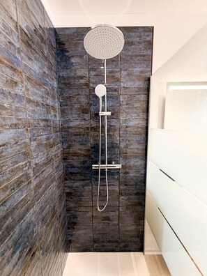 A shower with a round head, a handheld showerhead, and a handheld sprayer.