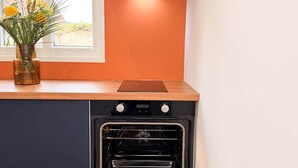 A kitchen with a built-in oven, a window with a view, and a decorative vase with flowers.