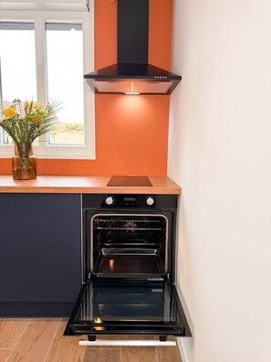 Une cuisine équipée d’un four encastré, une fenêtre offrant une belle vue et un vase décoratif avec des fleurs.