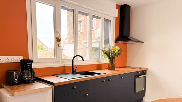 A kitchen with a window, a sink, a stove, and a dining area.