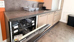 Eine kleine Küche mit Geschirrspüler, Spüle und einem Fenster mit Jalousien.
