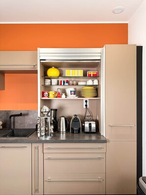 A kitchen with a built-in oven, a sink, and a countertop with various appliances and storage shelves.
